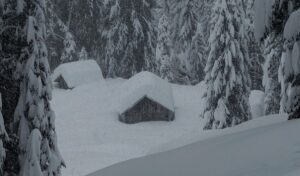 Starker Schneefall auf Holzhütten und Fichtenbäume