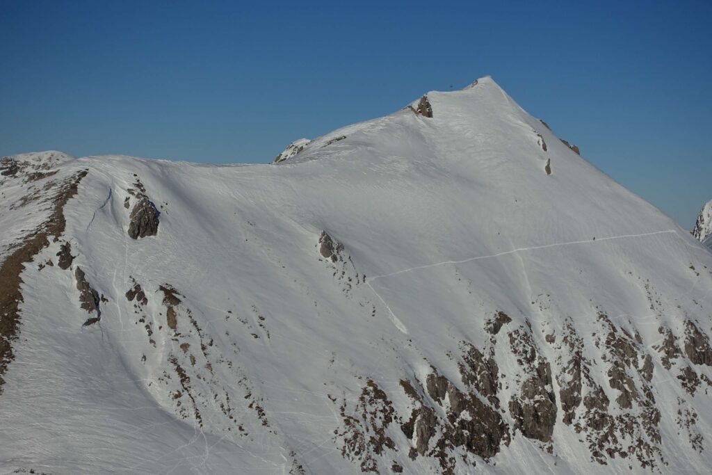 Hangquerung von drei Wintersportlern im steilen bis sehr steilen Gelände oberhalb von Felsabbrüchen.